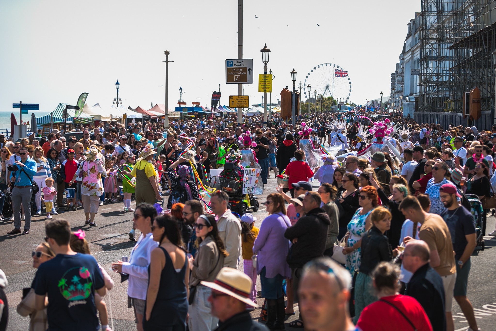 Wide shot of 2023 carnival crowds and parade with ferris whel in the back ground.